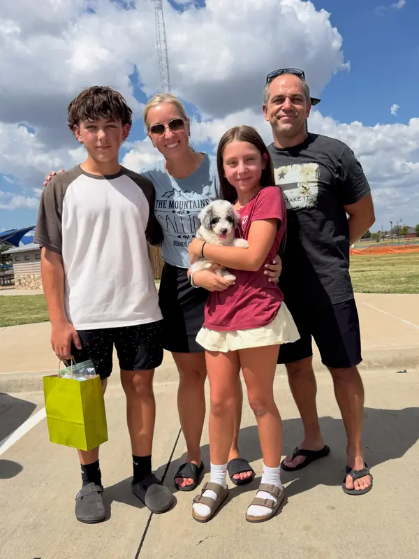 A family on gotcha day, taking home their Bernedoodle puppy from KK Doodles